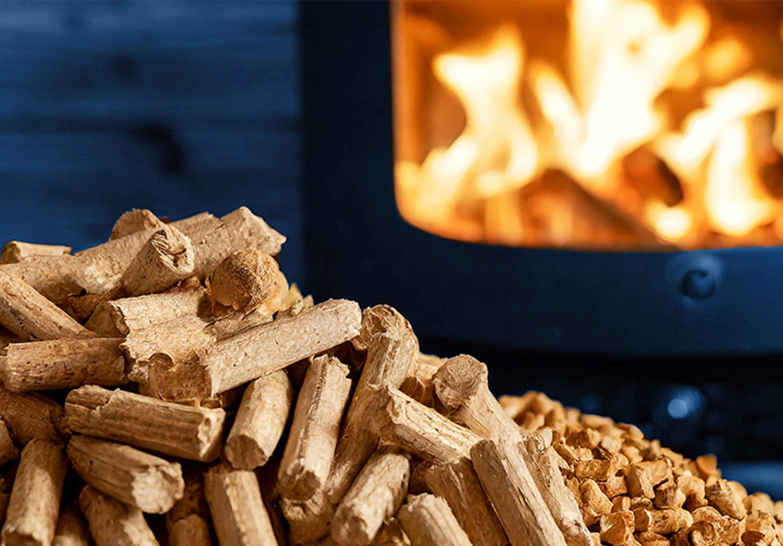 Holzpellets mit grünen Blättern auf Holz. Im Hintergrund geschichtete Holzscheite.