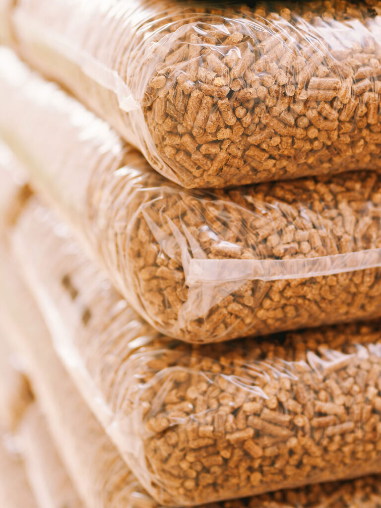 Holzpellets mit Blättern und Zapfen auf Holztisch – Symbol für natürliche Energiequellen.